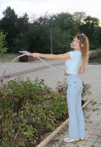 Саманта поливает розы с шланга