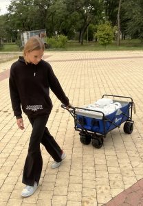 Девочка тянет тележку с водой
